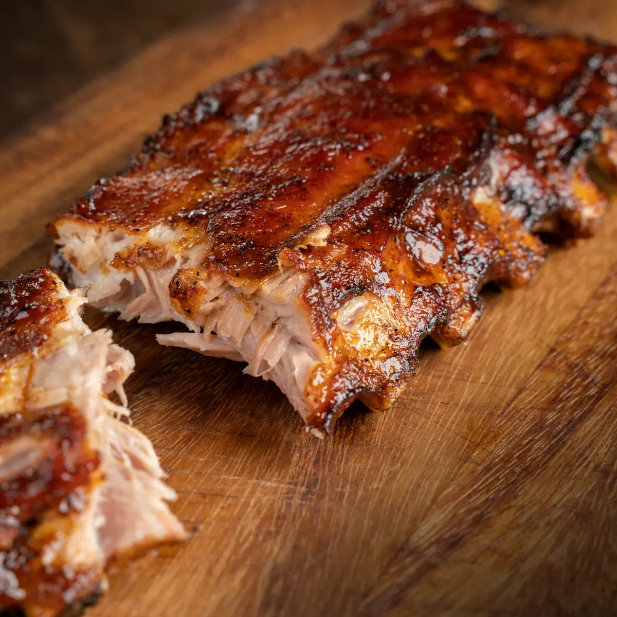 Close-up of a MR MIKES ribs plate with glazed rack of ribs served on a wooden board