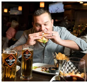 Guest eating a burger and enjoying beer at MR MIKES