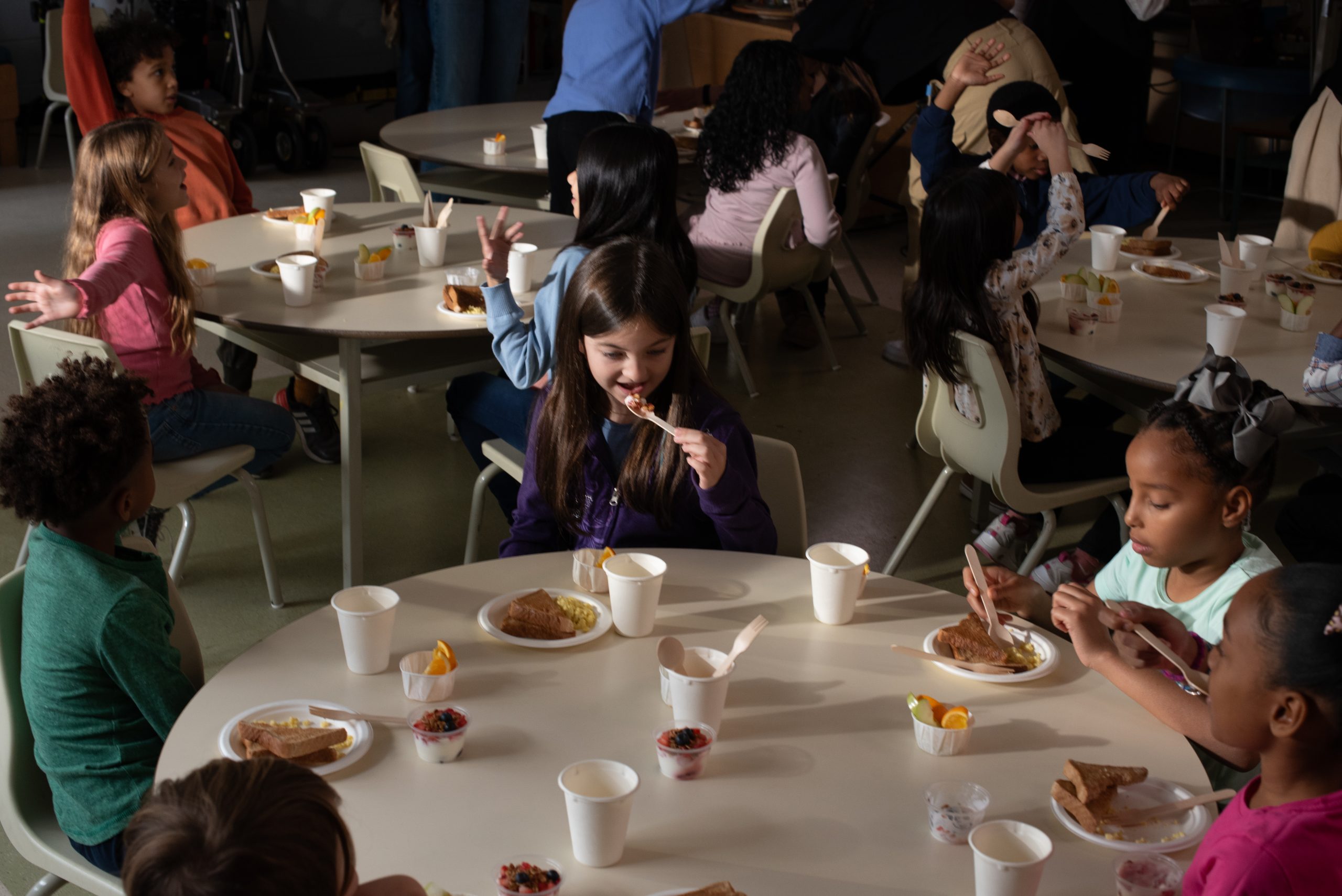 Children enjoying meals as part of the Make Happy Tummies initiative, seated at tables with snacks and drinks.
