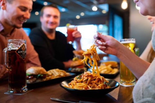 Group of people enjoying pasta, burgers, and drinks at MR MIKES Steakhouse Casual